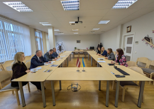 Sanāksmju telpa, U veida galds, 8 cilvēki no abām pusēm sēž pie galda