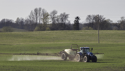 Traktors ar smidzināšnas iekārtu veic lauka miglošanu