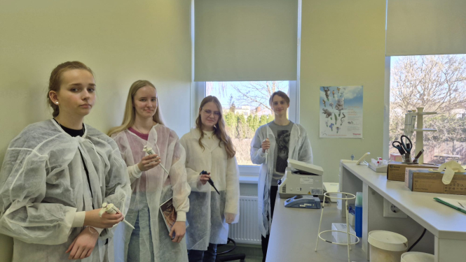 četri jaunieši - trīs meitenes un pusis stāv laboratorijā