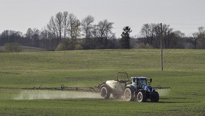 Traktors ar smidzināšnas iekārtu veic lauka miglošanu