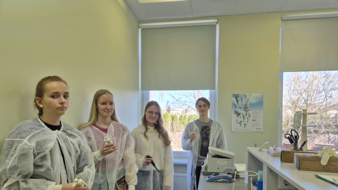 četri jaunieši - trīs meitenes un pusis stāv laboratorijā