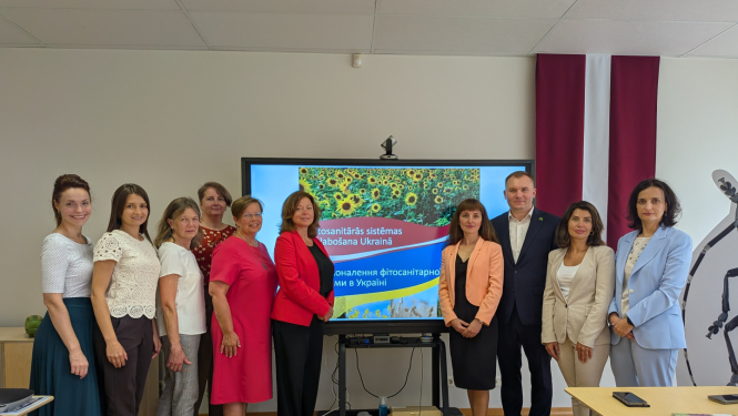 Grupas bilde: 6 cilvēki no labās (LV) puses un 4 cilvēki no kreisās (UA), fonā LV karogs un ekrāns