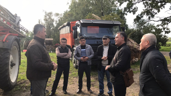 Varāki cilvēki sarunājas saimniecībā, fonā tehnika