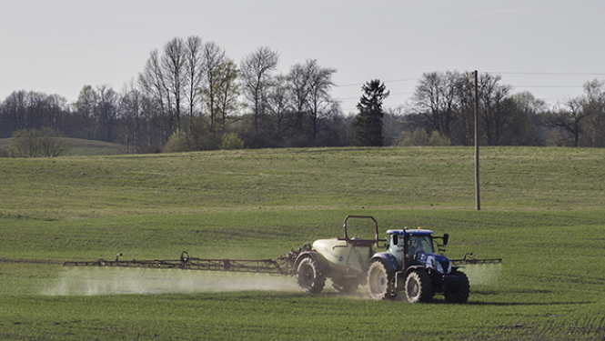 Traktors ar smidzināšnas iekārtu veic lauka miglošanu