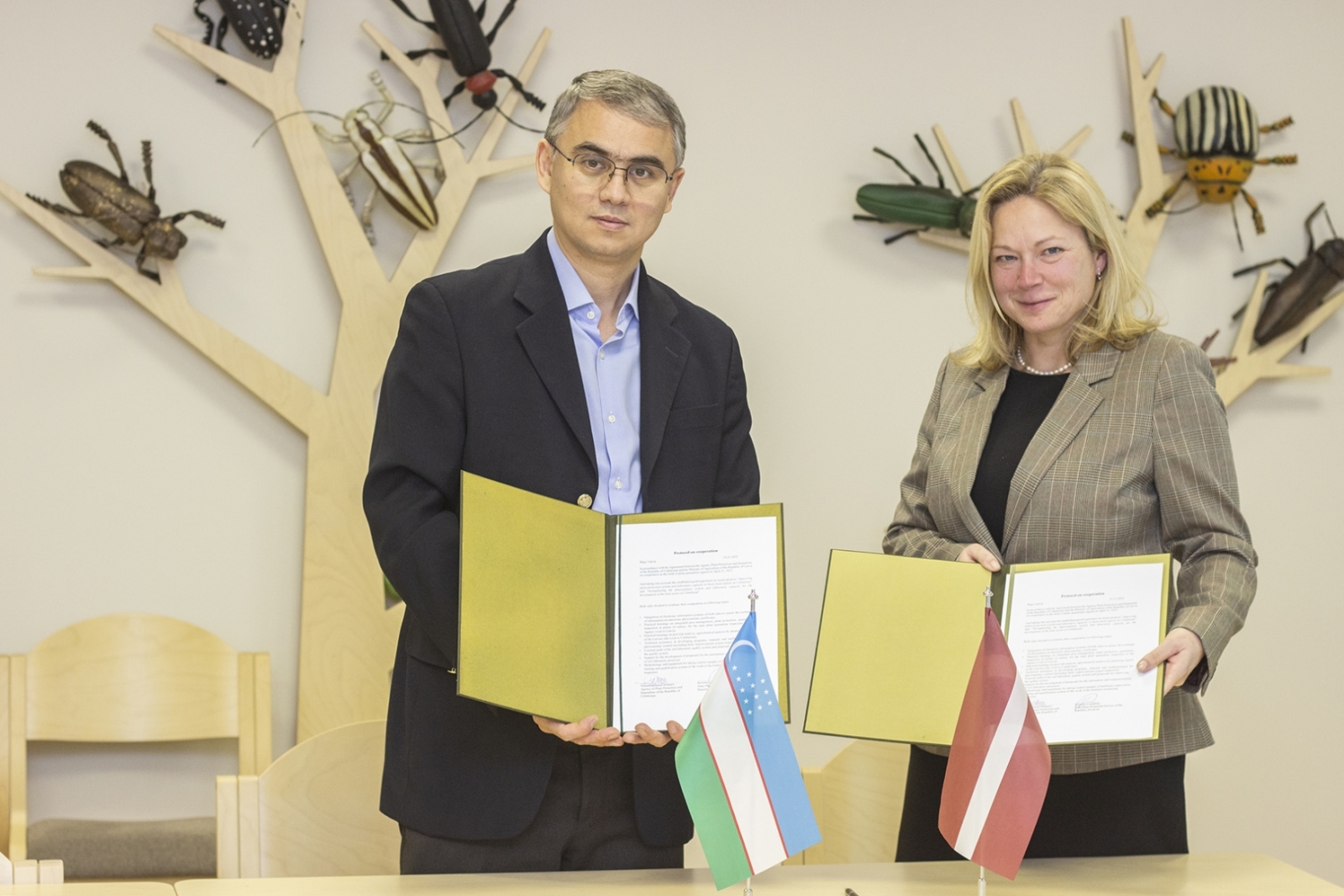 VAAD direktore un Uzbekistānas eksperts rāda atvērtos vākos parakstīto dukumentu