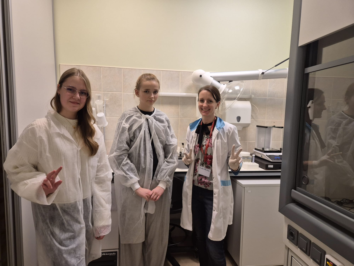 trīs meitenes stāv  laboratorijā