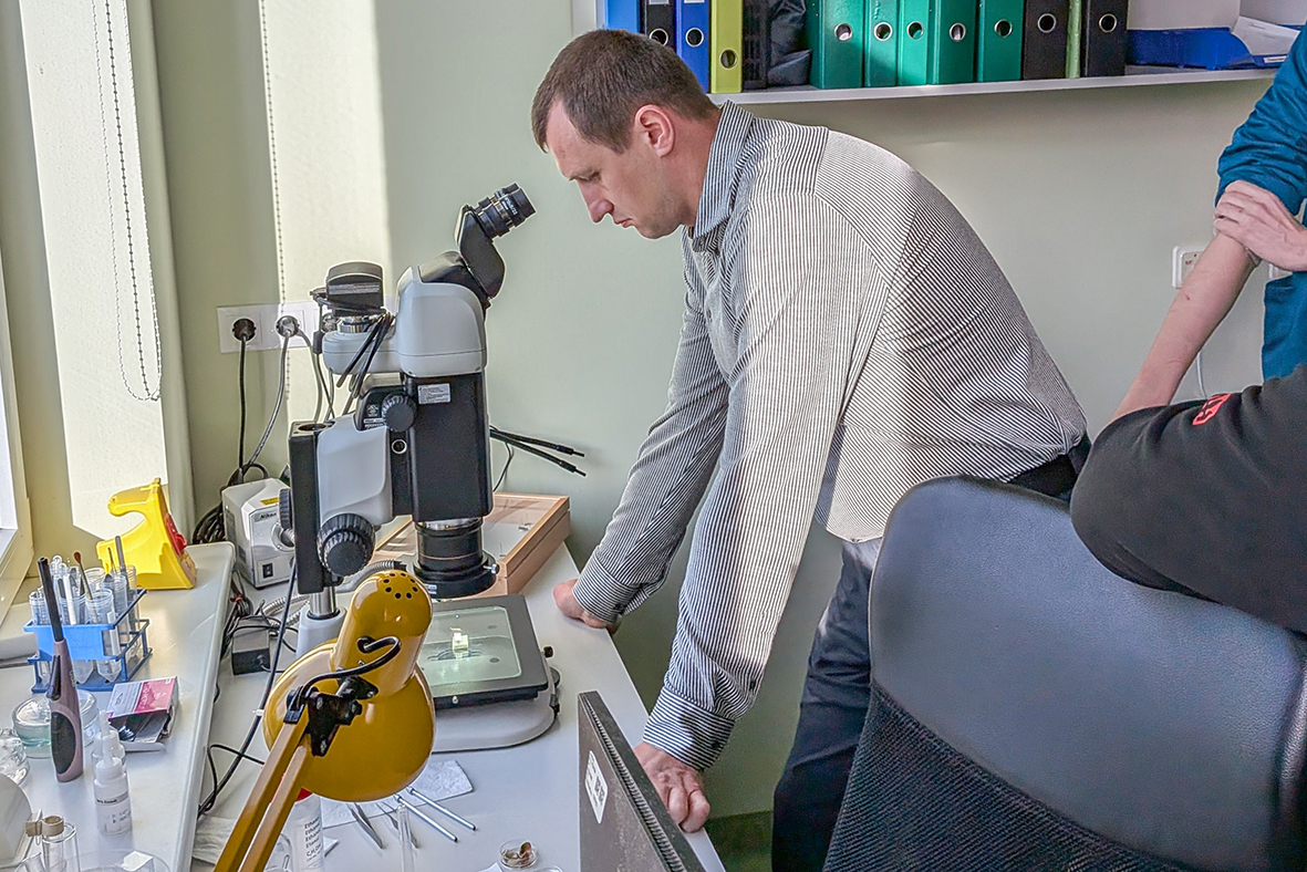 Tkačuks skatās mikroskopā entomoloģijas kabinetā