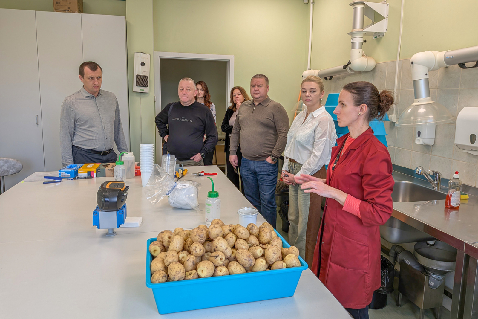 Paraugu apstrādes kabinets - centrā galds, trauks ar kartupeļu paraugiem, eskperte stāsta Ukrainas kolēģiem 