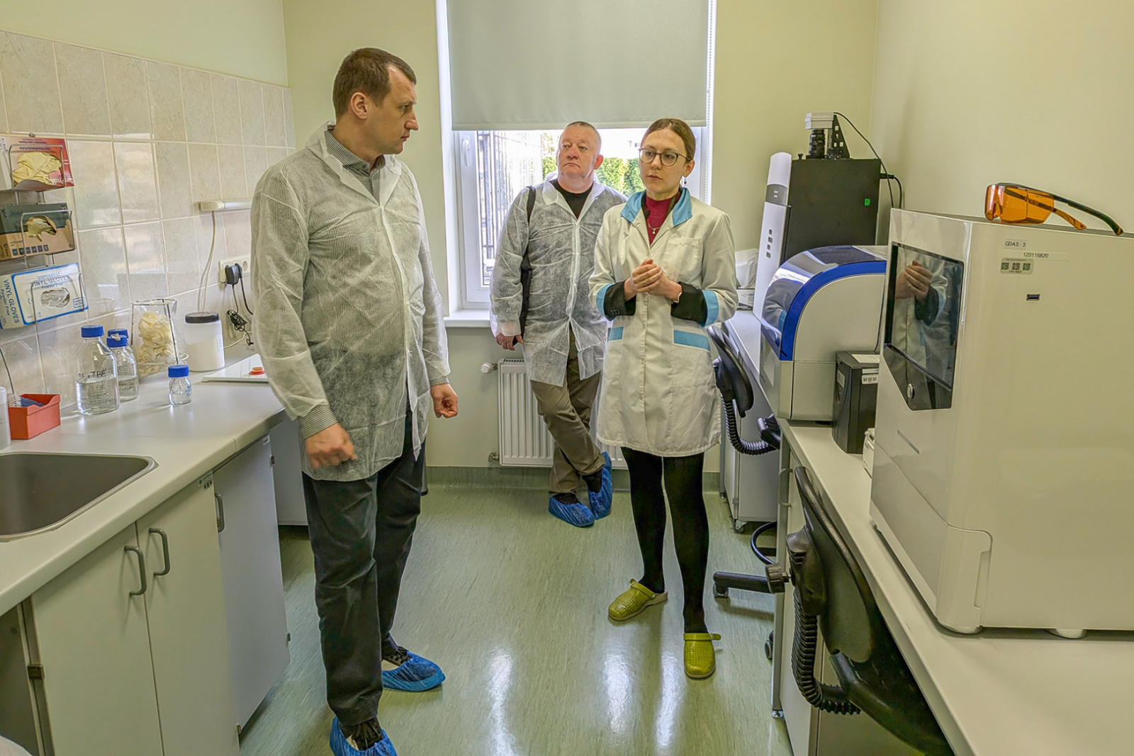 Bakteriologu kabinets - priekšplānā aprīkojums, trīs cilvēki baltos halātos - VAAD eksperte un ukraiņi