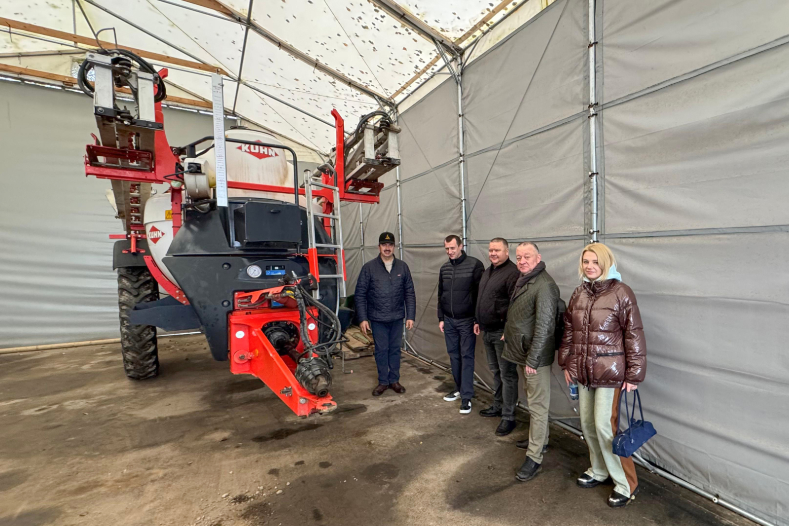 Angārā pie traktortehnikas Arnolds Jātnieks un 4 Ukrainas delegācijas pārstāvji