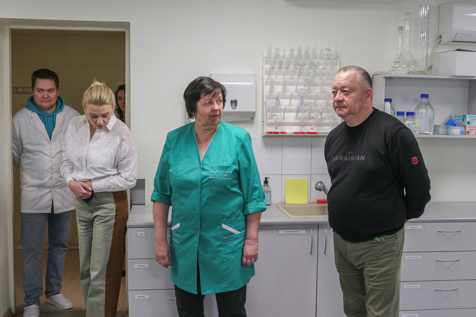 Agroķīmijas laboratorijas apmeklējums - četri cilvēki, fonā laboratorijas aprīkojusm