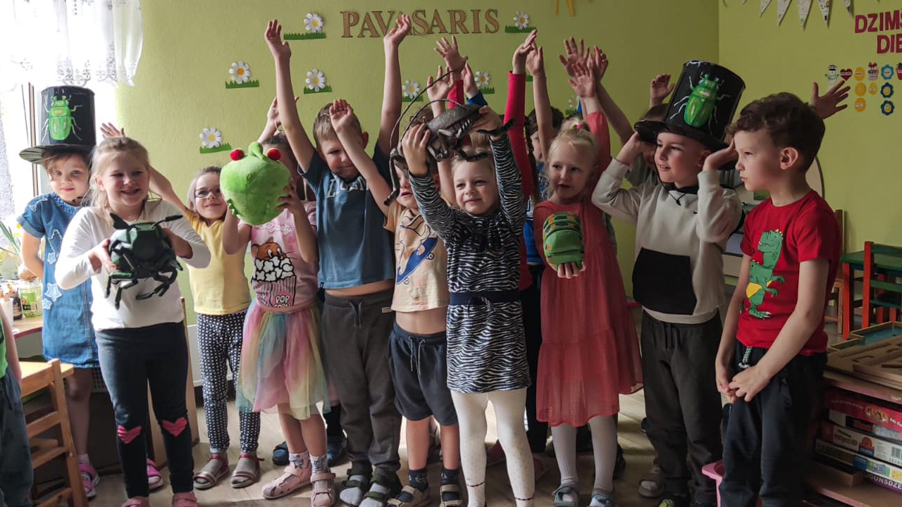 Bērnu grupiņa, priecīgi ar paceltām rokām