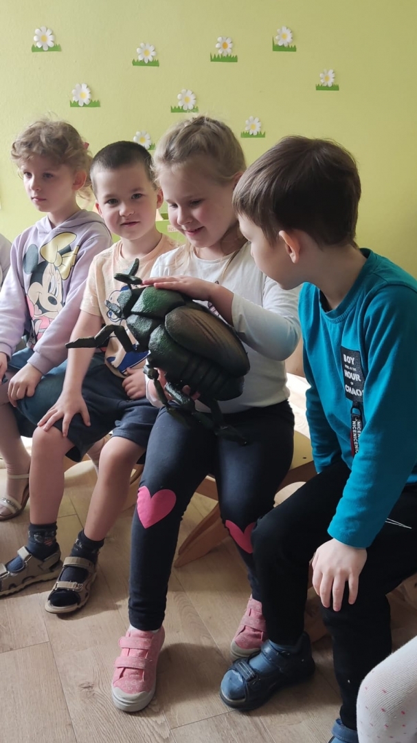 Bērni tur rokā kukaiņu maketu un pēta