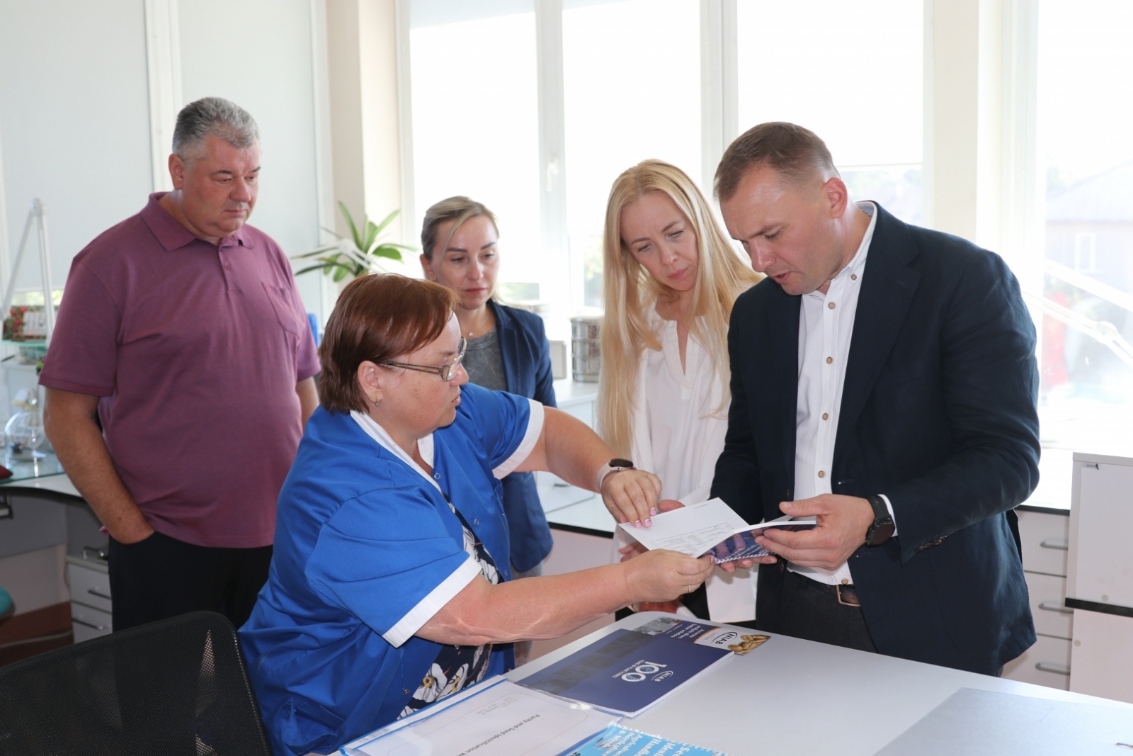 Darbiniece demonstrē informatīvo materiālu