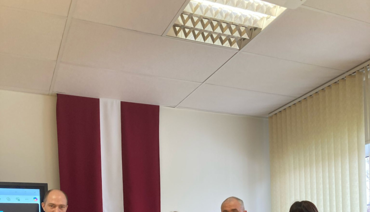 Attēls ar 5 cilvēkiem un Latvijas, sarkanbaltsarkano krogu fonā.